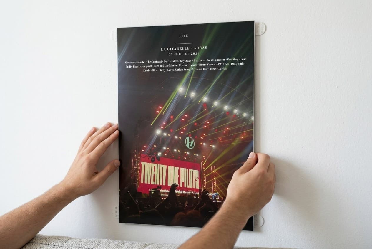 Pose d'un print Dibond PrintMyConcert à plat contre un mur blanc, attaches adhésives visibles