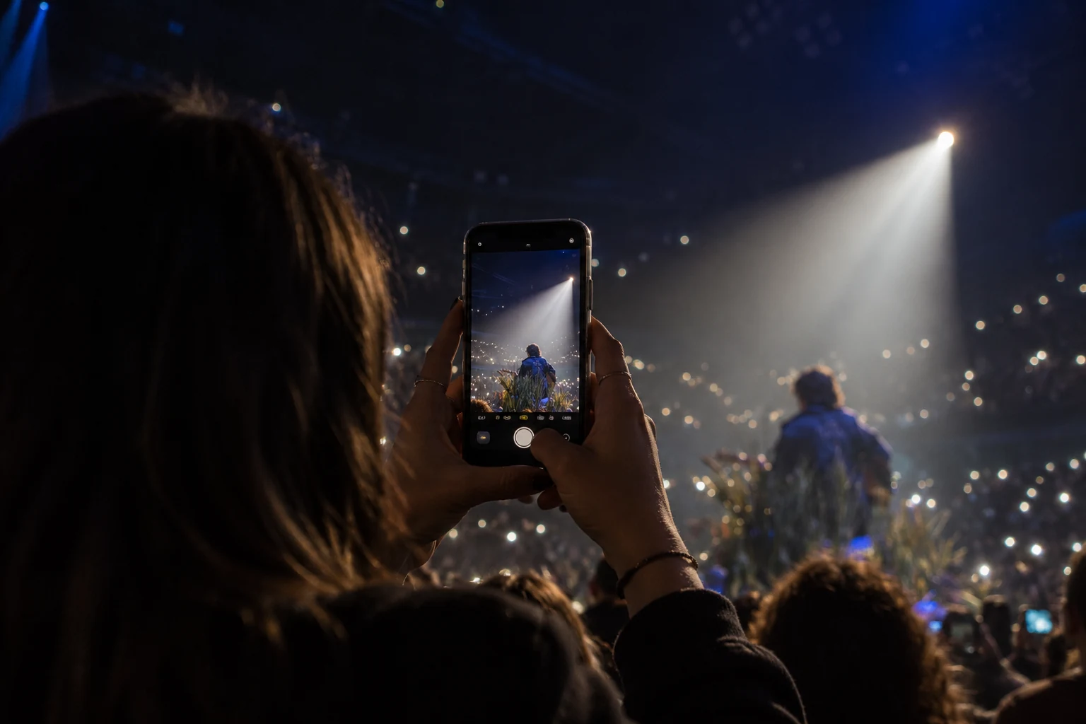 Une personne photographie le concert, vue par-dessus son épaule